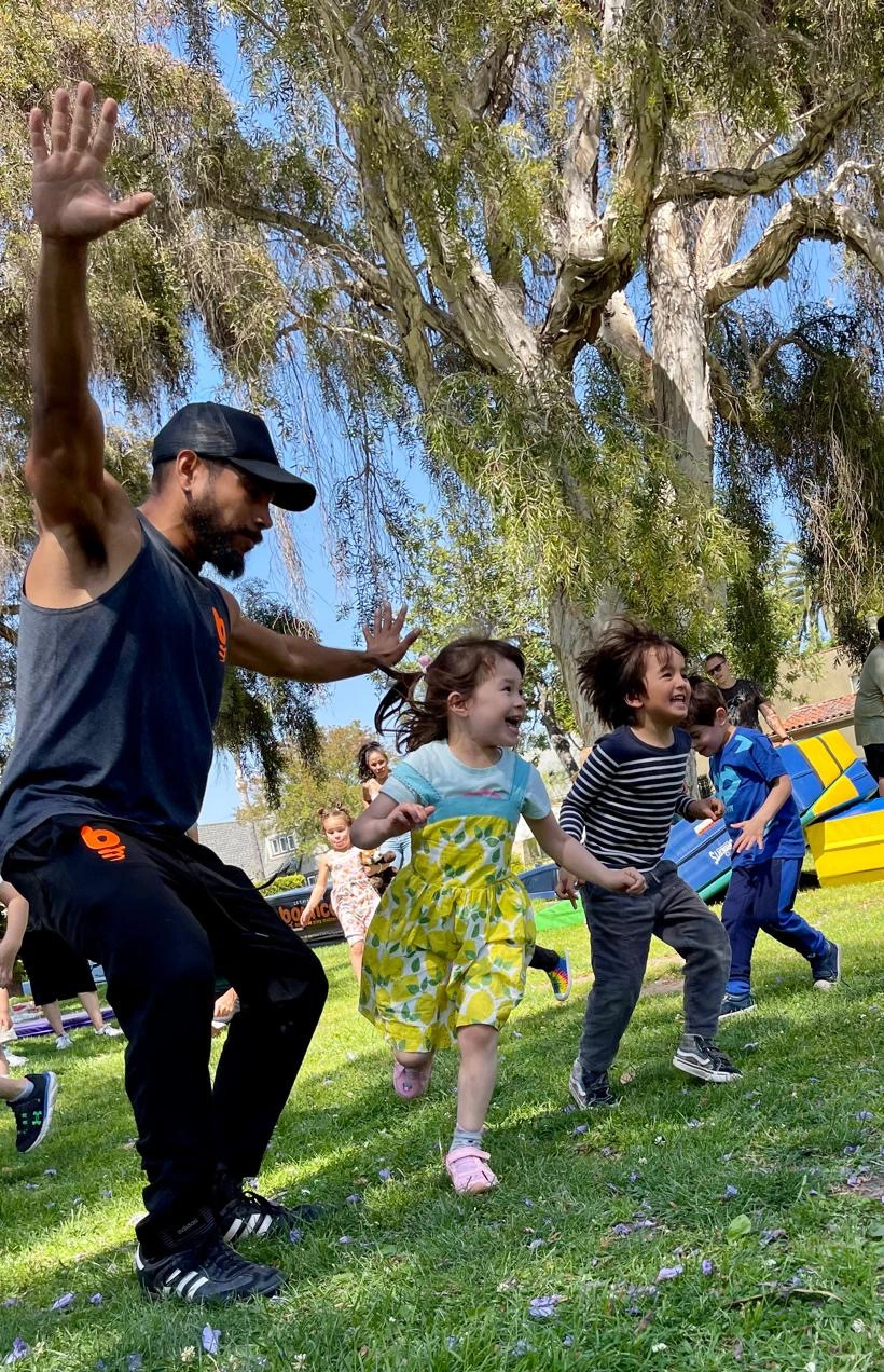 Coach leading children running through the park